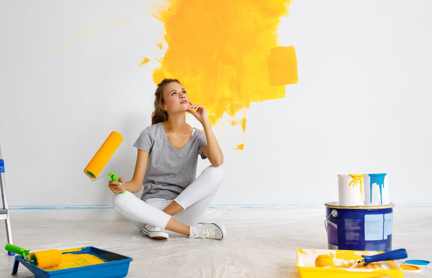 Happy young woman paints wall